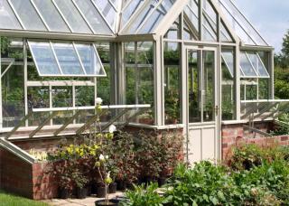 Aluminium-framed greenhouse with brick foundations.